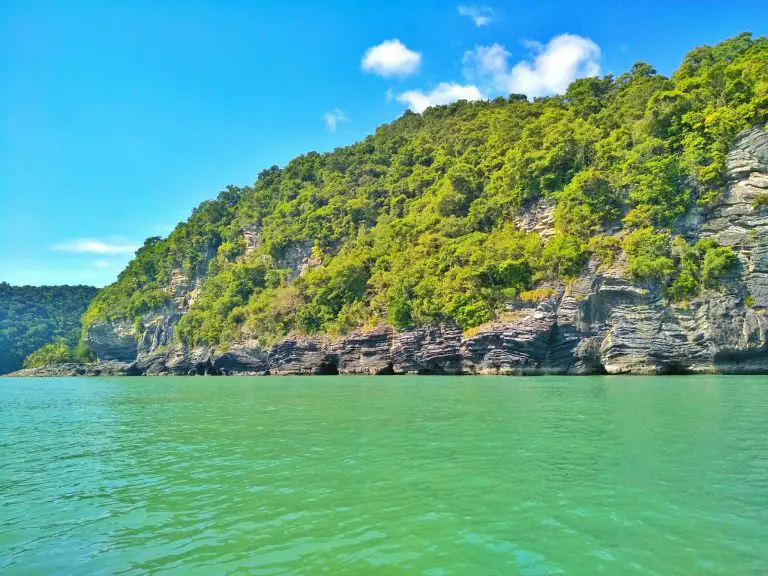 green sea in Thailand with pancake rock formations in the background in Nakhon Si Thammarat province