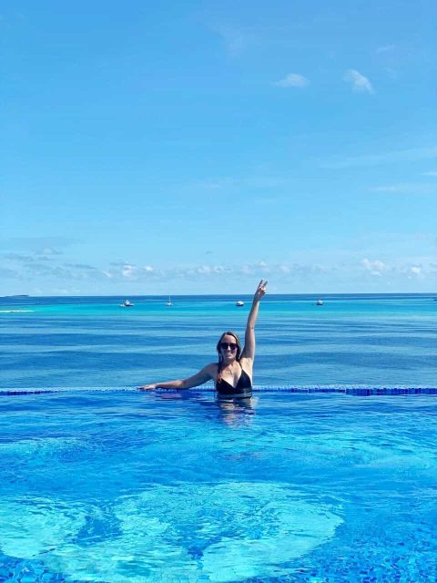 Me in a rooftop infinity pool on the local island of Thulusdhoo with a turquoise ocean view behind me.