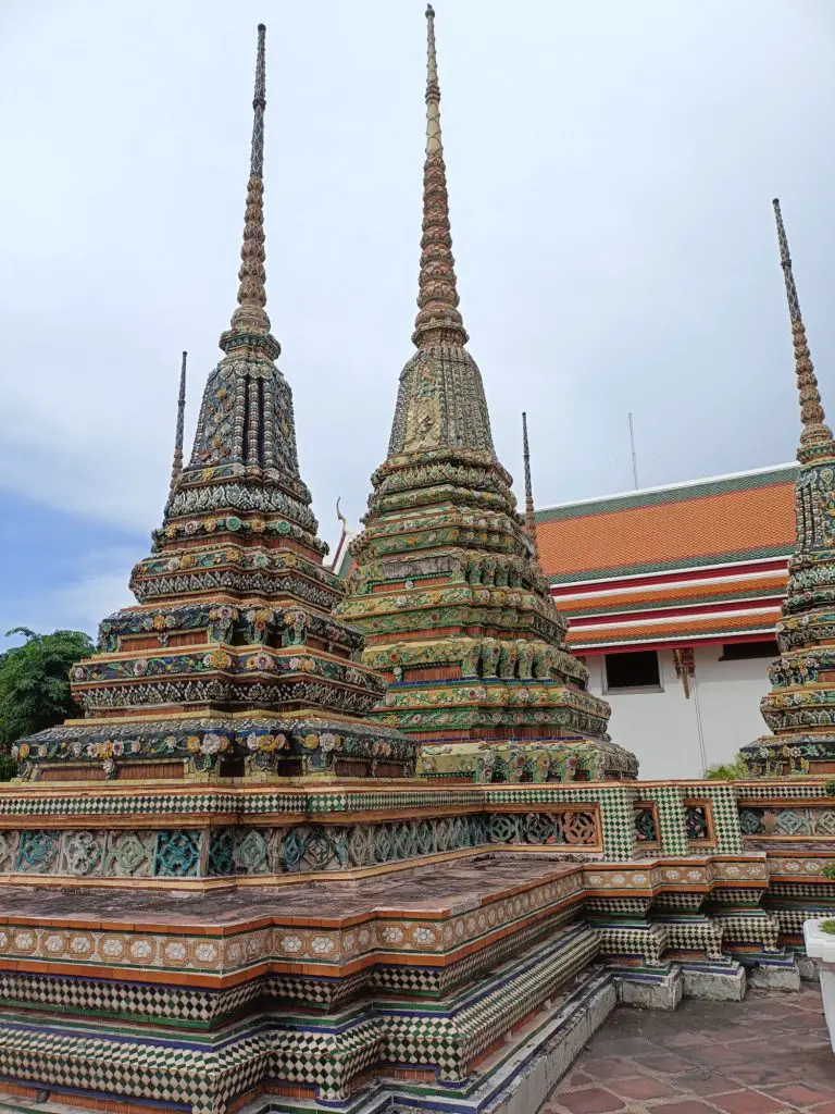 Temples in Thailand at Wat Pho in Bangkok with a blue and cloudy sky.